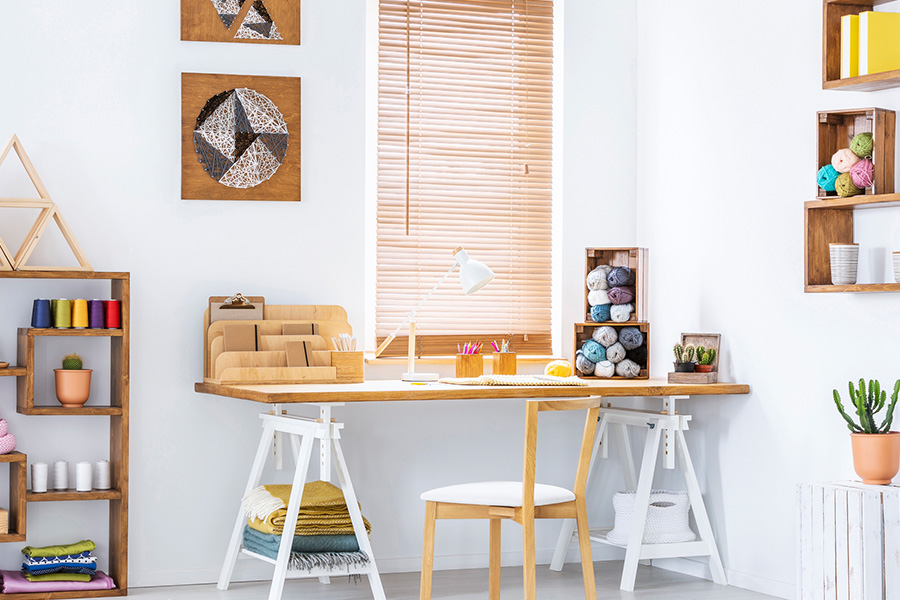 Light oak wood blinds add a natural element to your living space.
Wood blinds in a white and airy craft corner.