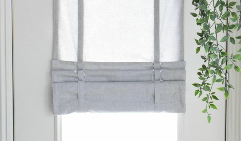 With a tiered tumble shade in Atlanta, you can block sun glare all year round. Gray rolled tumble shade on a glass door